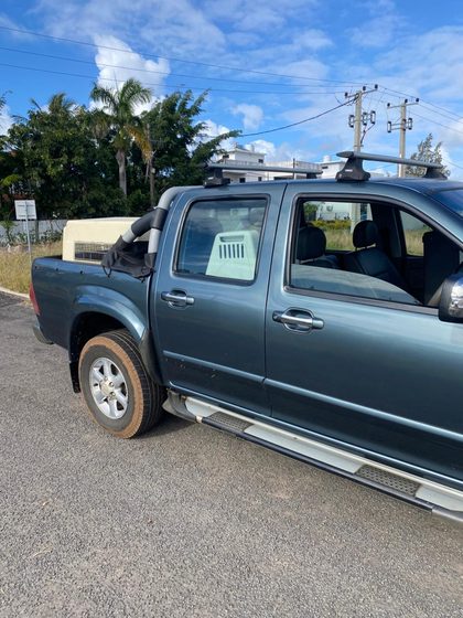 Dark green pickup truck with a ventilated animal crate secured in the tray, parked outdoors